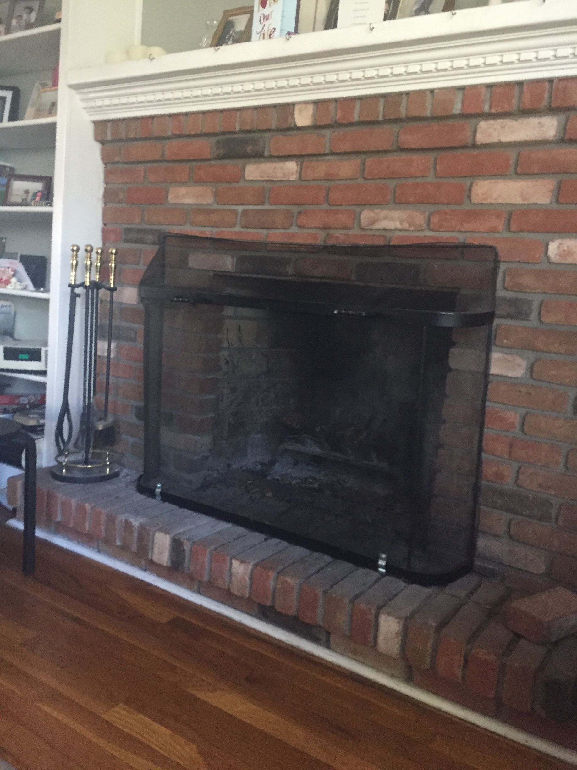 Brick fireplace with black glass doors and a white mantel in a living room