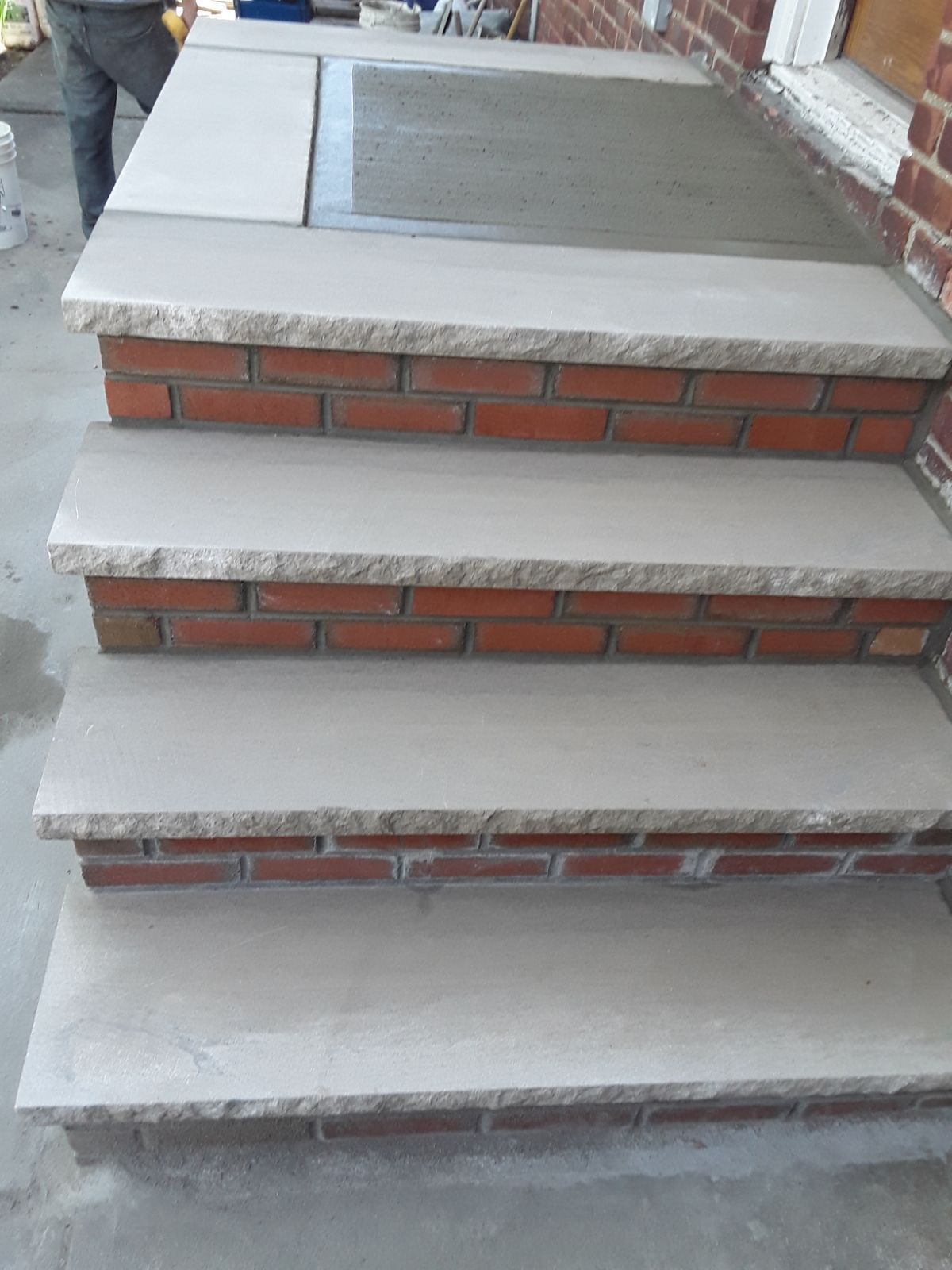 Brick steps under construction with concrete treads and brick risers on a porch stairway