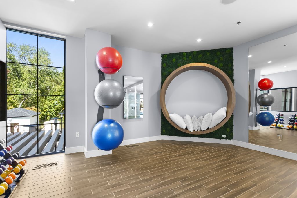 Bright room with exercise balls, a round wall chair, and mirrors on a wood floor