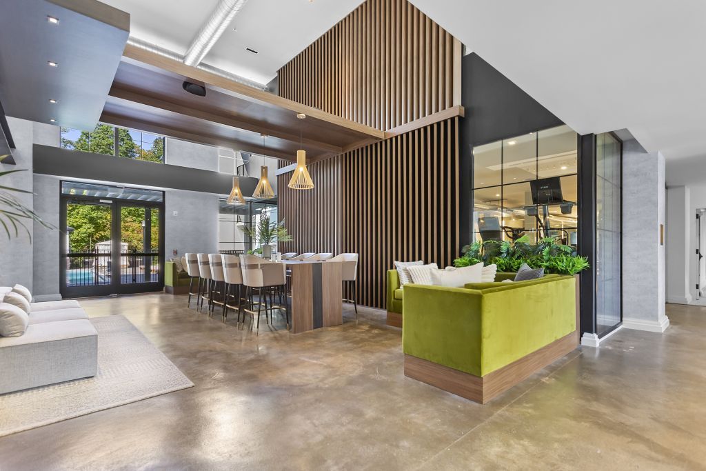 Modern open-plan lobby with dining table, green reception desk, and wood slat accents