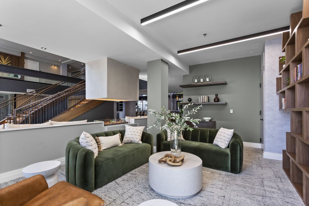 Modern living room with green sofas, round white coffee table, and open shelving in a bright interior