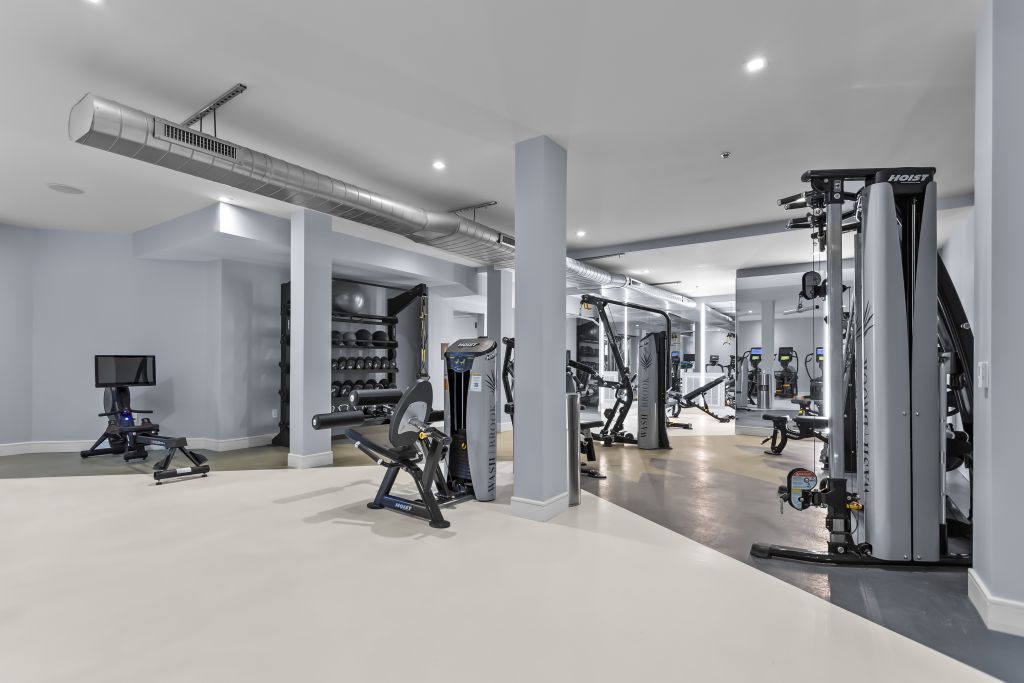 Modern gym interior with exercise machines, mirrors, and bright overhead lighting