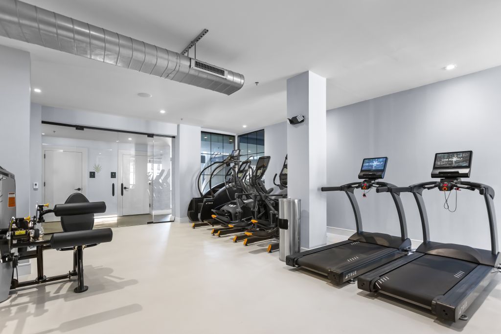 Modern gym with treadmills, weight equipment, and bright white interior