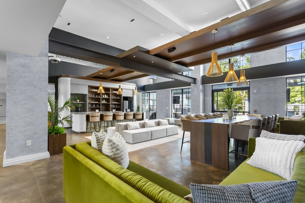 Modern open-plan lounge with green and white sofas, wood accents, and large windows