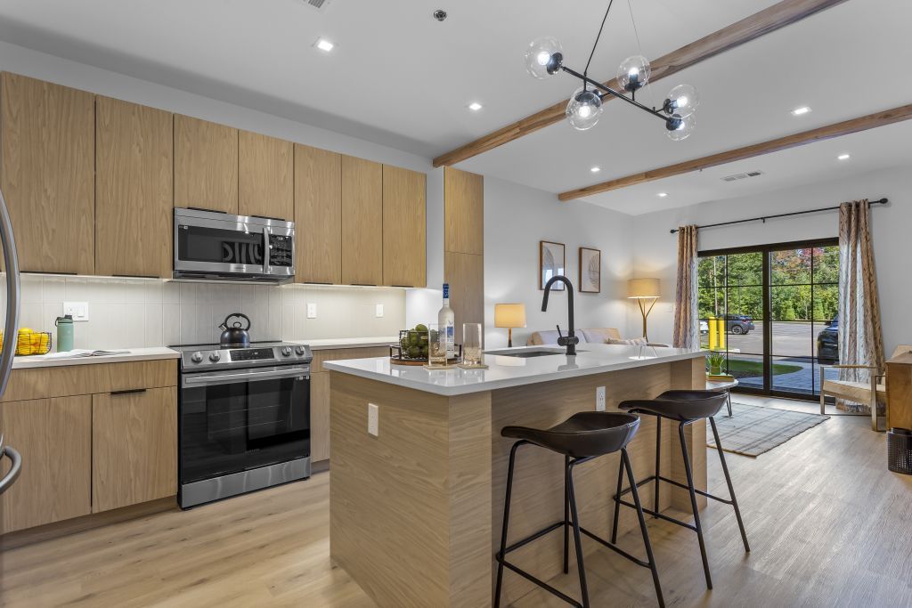Modern kitchen with wood cabinets, island seating, and sliding glass doors to a patio.