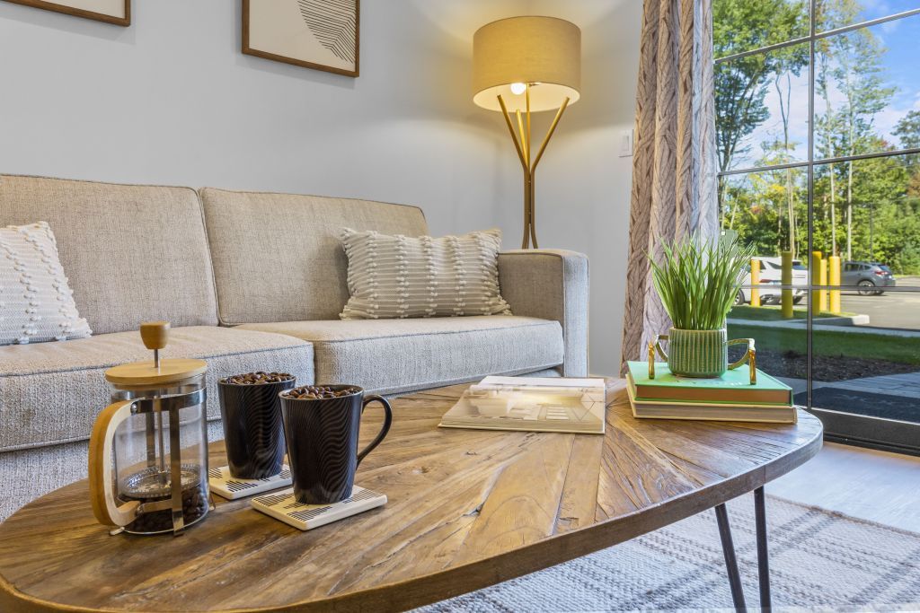 Bright living room with beige sofa, wooden coffee table, lamp, and glass doors to a sunny patio