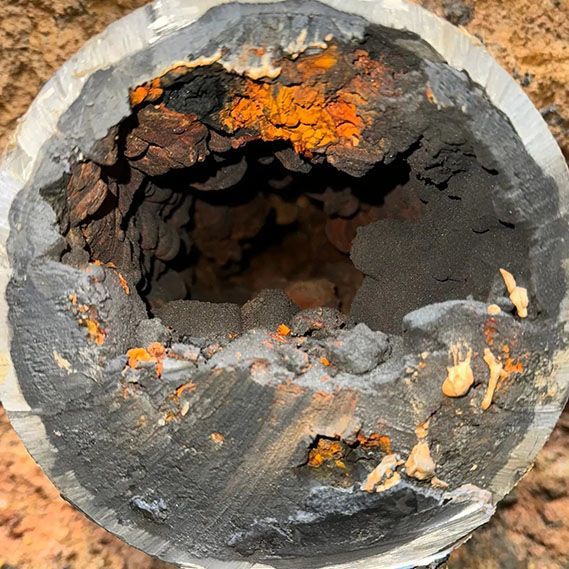 A close up of a rusty pipe with a hole in it