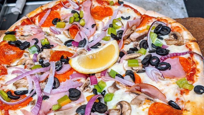 A colorful custom pizza loaded with fresh vegetable toppings, showcasing the 'Make Your Own Pizza' night at Red Banjo Pizza.