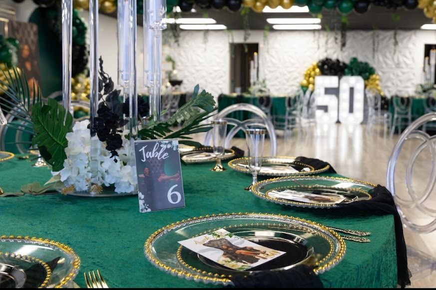 Green-and-gold banquet table setup with plates, candles, and a large white “50” centerpiece