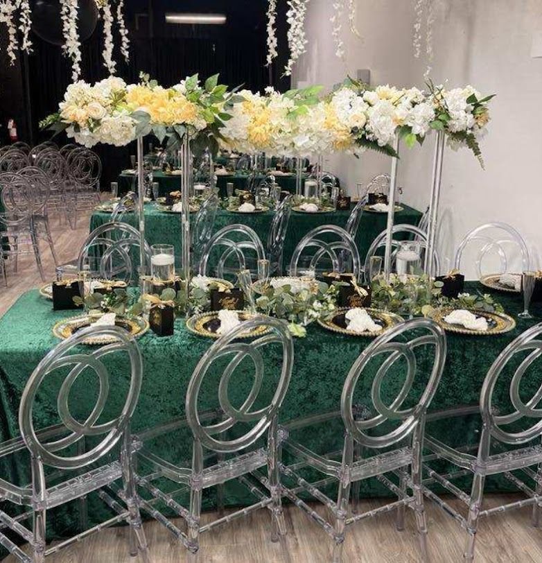 Elegant banquet table with green tablecloth, white floral centerpieces, and clear acrylic chairs