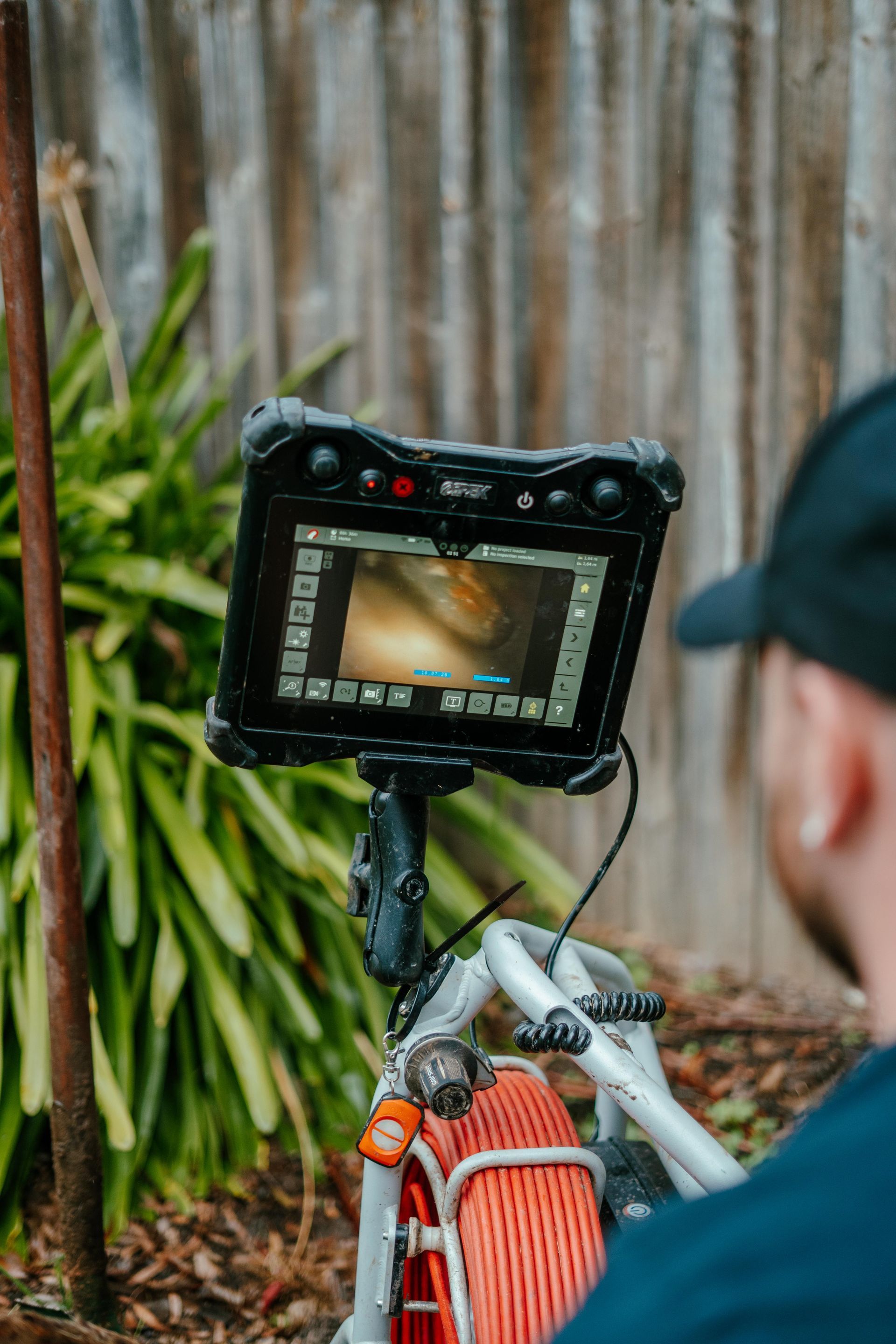 Camera viewfinder filming a bicycle wheel with an orange frame in front of a corrugated metal wall — Aquafix Plumbing Services in Bowral, NSW