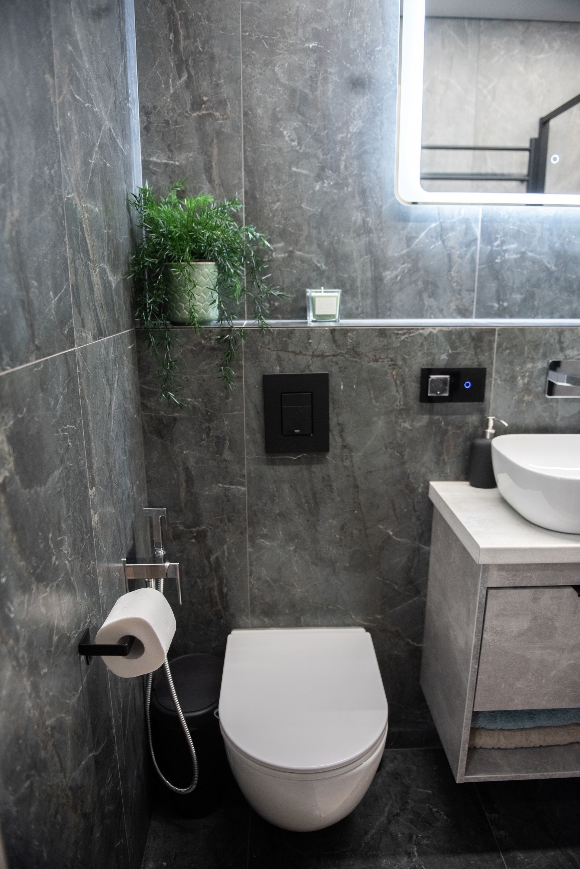 Baigtas modernus vonios kambarys po santechnikos darbų Vilniuje. Sumontuotas potinkinis WC rėmas ir tamsios plytelės.