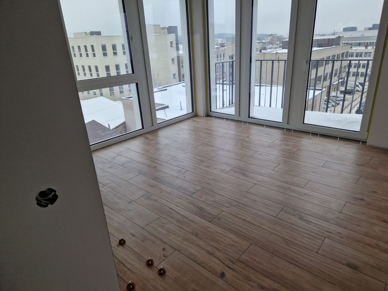 Medžio imitacijos plytelės ką tik išklotos naujame bute su vaizdu pro langą.