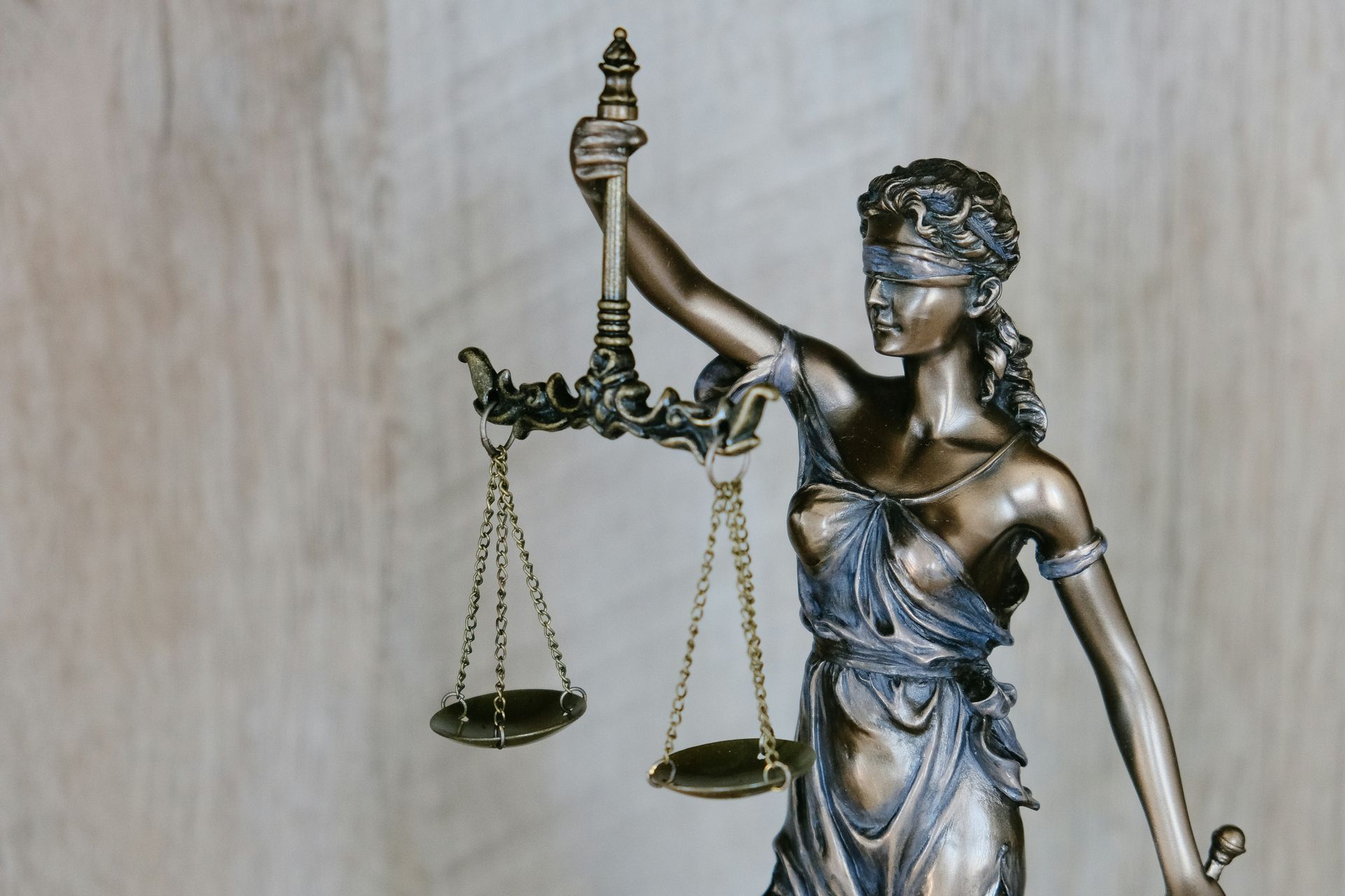 Statue of Lady Justice holding scales, blindfolded, bronze color.