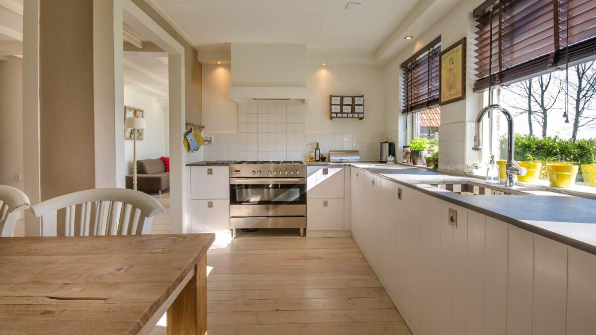 Bright kitchen with white cabinets, stainless steel stove, and wooden blinds.
