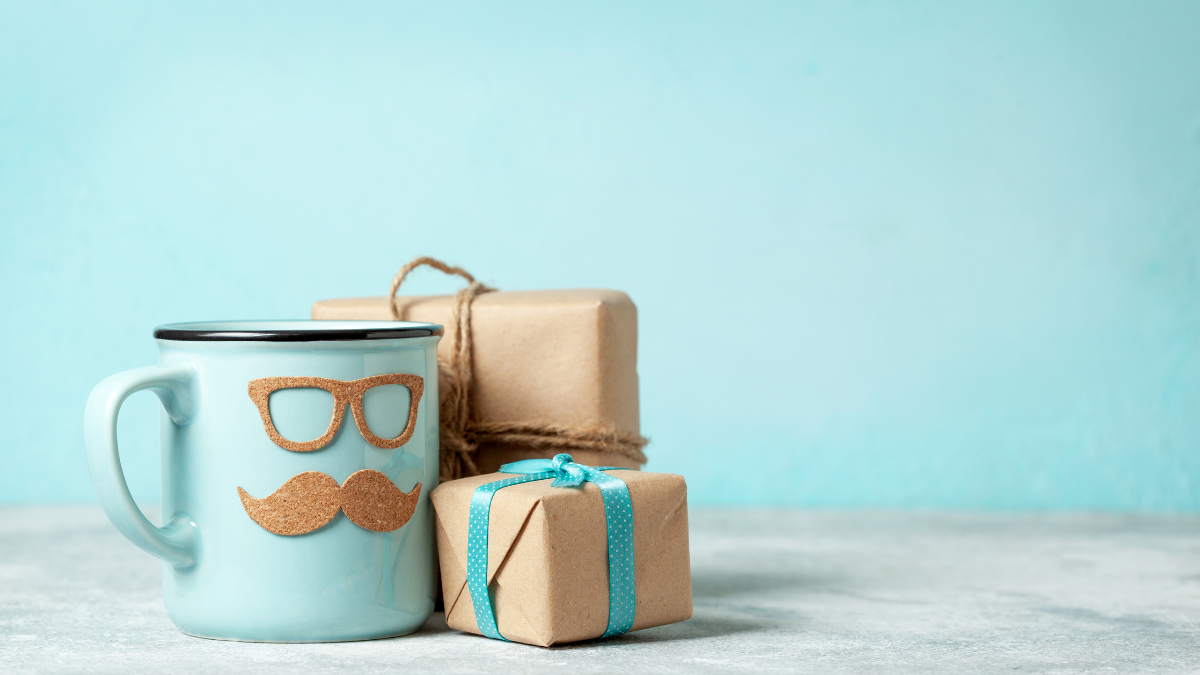 Blue mug with glasses and mustache, with wrapped gifts on a table, against a light blue background.