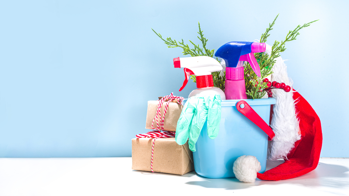 A bucket filled with cleaning supplies and a Santa hat on a table. Total Clean holiday clean.