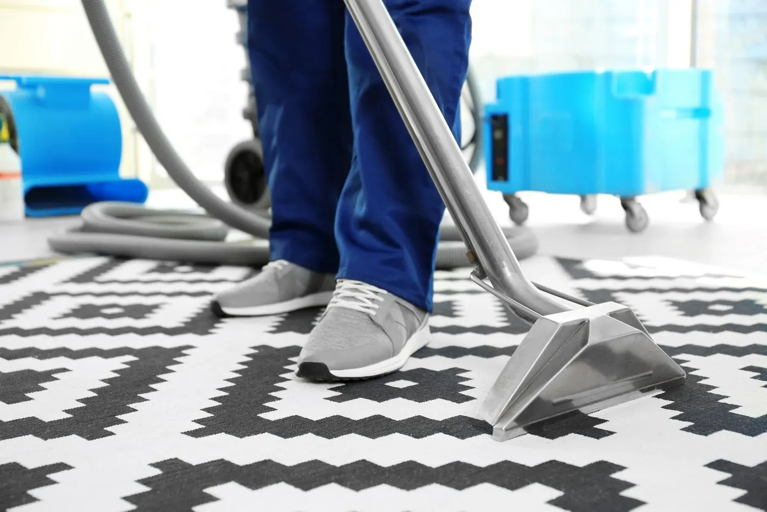 A person is cleaning a rug with a vacuum cleaner.