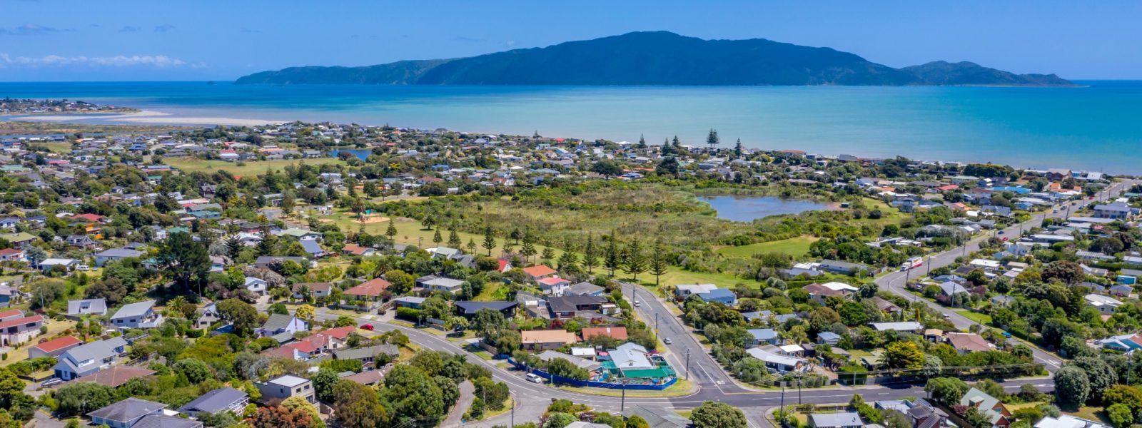 An aerial view of a residential area next to the ocean with a mountain in the background.