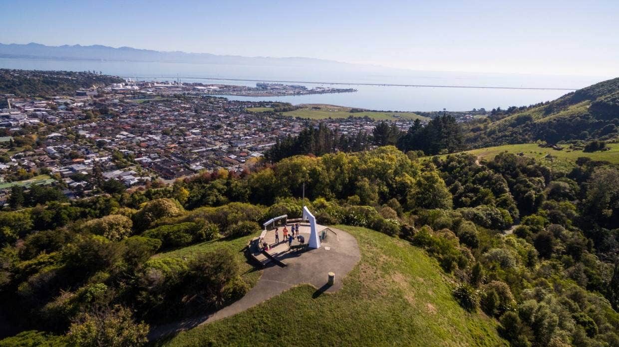 An aerial view of a statue on top of a hill overlooking a city.