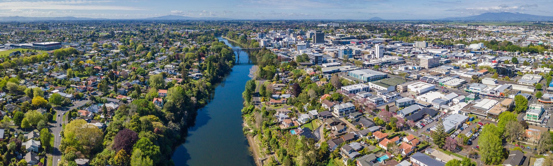An aerial view of a river running through a city surrounded by trees.