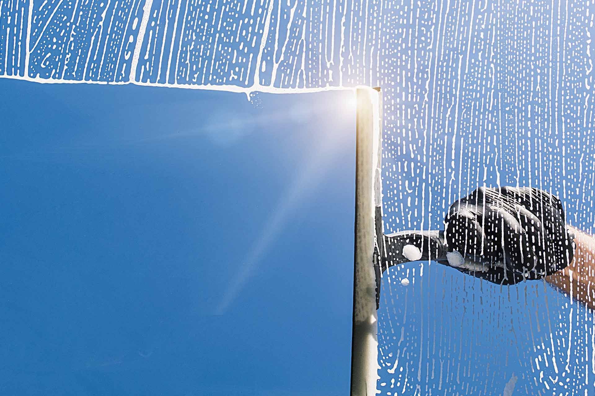 A person is cleaning a window with a squeegee.