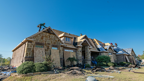 Damaged stone house with a collapsed roof under a clear blue sky in a dry, grassy area