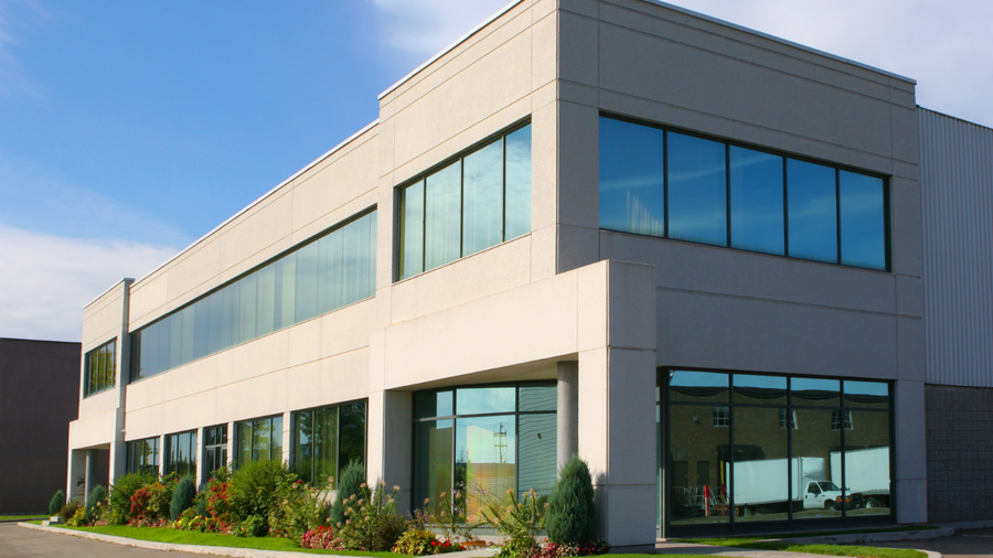 Modern two-story office building with large windows and landscaped greenery