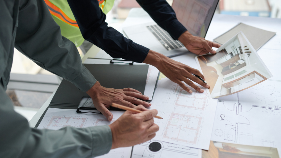 Hands reviewing charts and documents around a desk in a business meeting