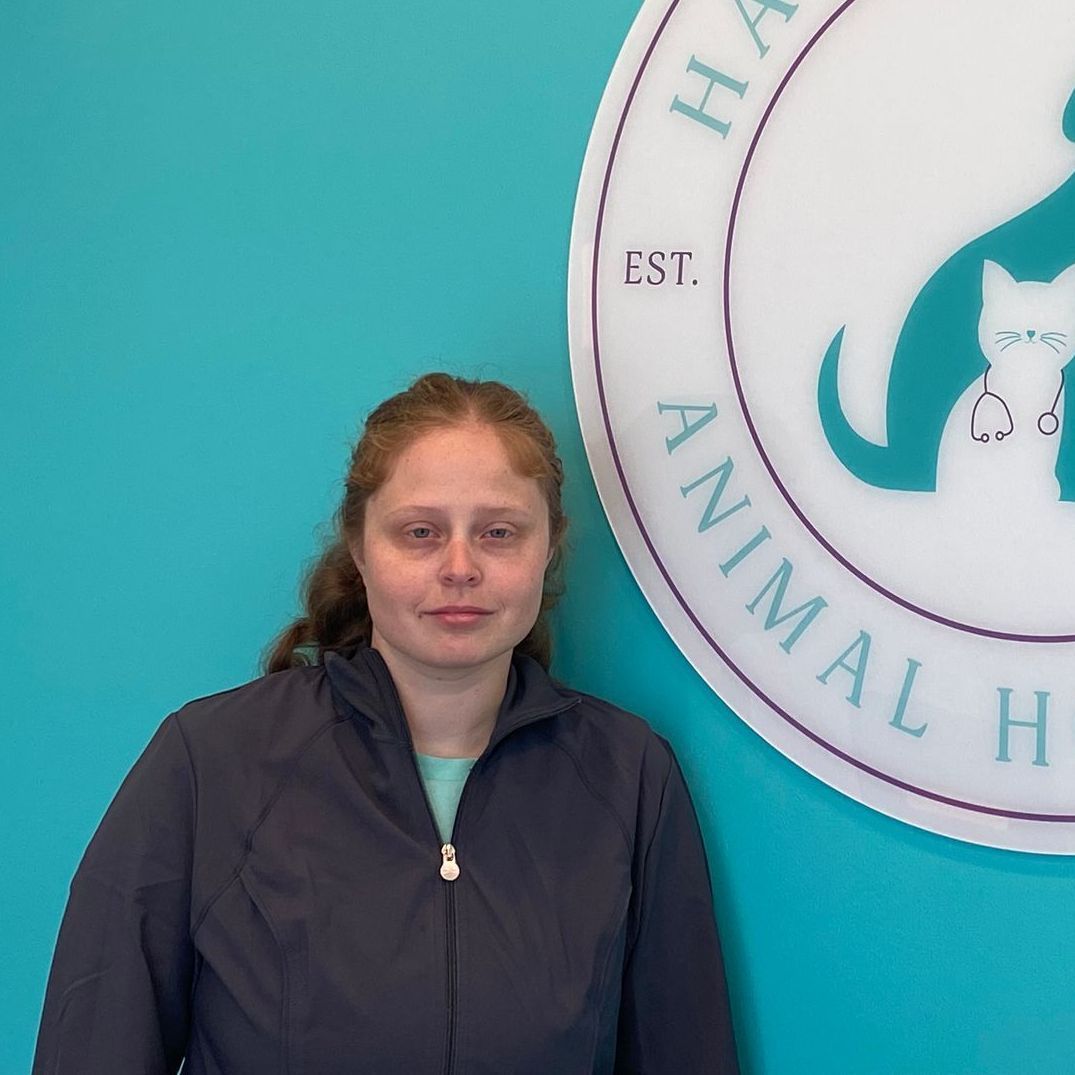 A woman stands in front of a sign for harmony hill animal hospital