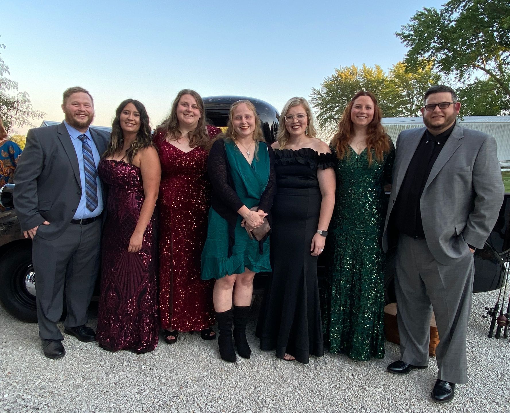 A group of people are posing for a picture in front of a limousine.