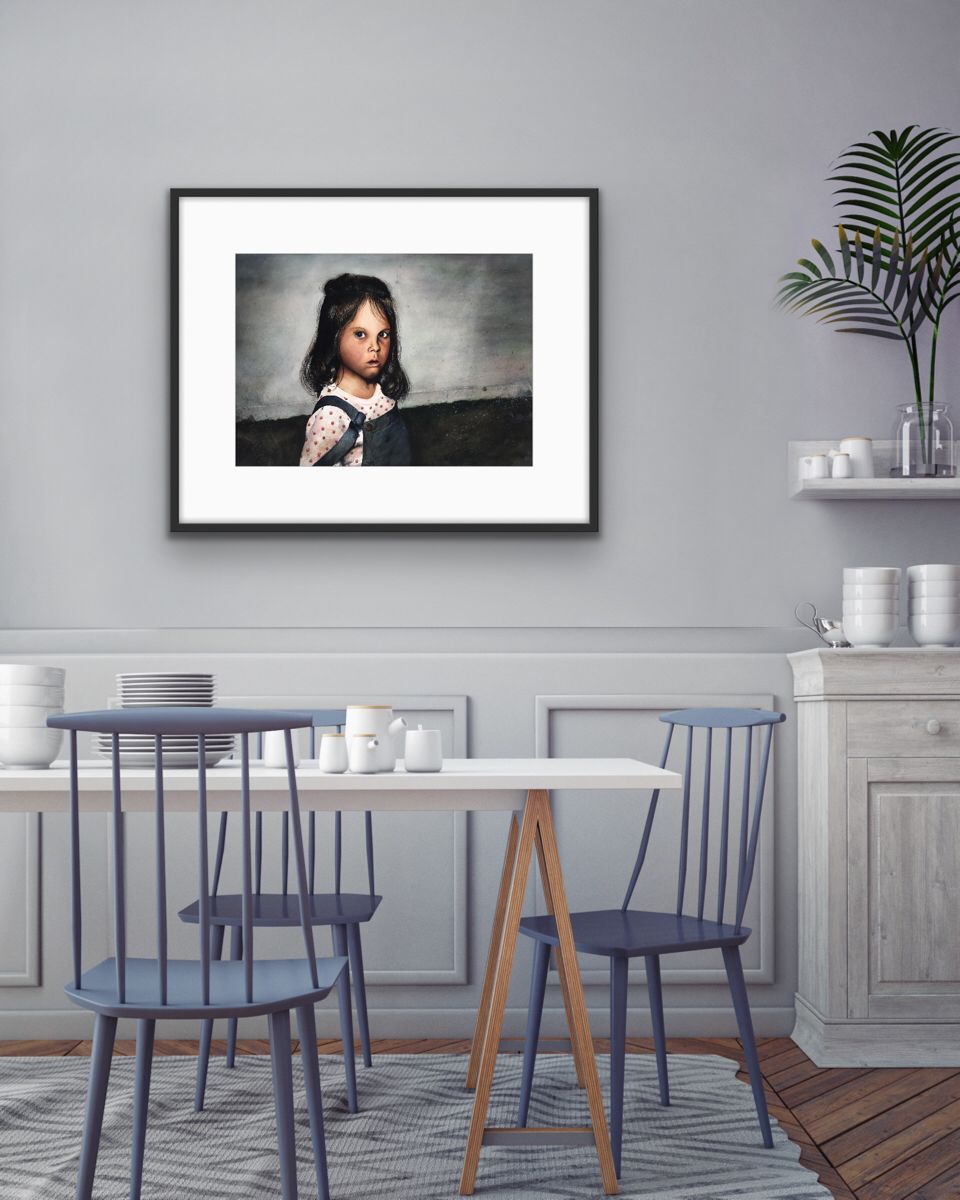 Dining room with a framed portrait, two blue chairs, a white table, and a sideboard with dishes and a plant.
