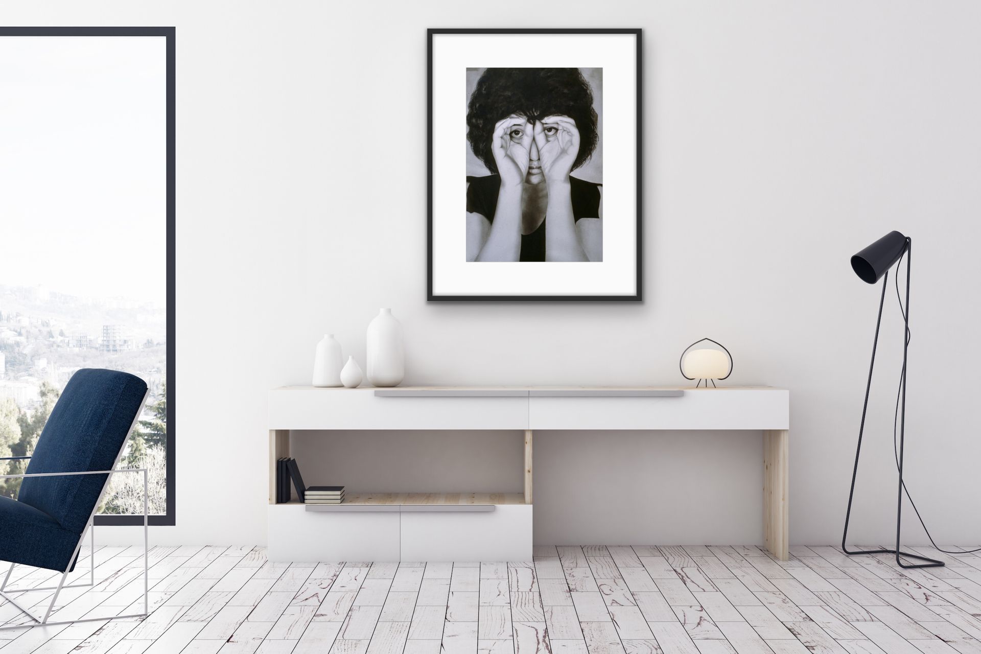 Minimalist white room with desk, chair, floor lamp, and framed black-and-white portrait on the wall