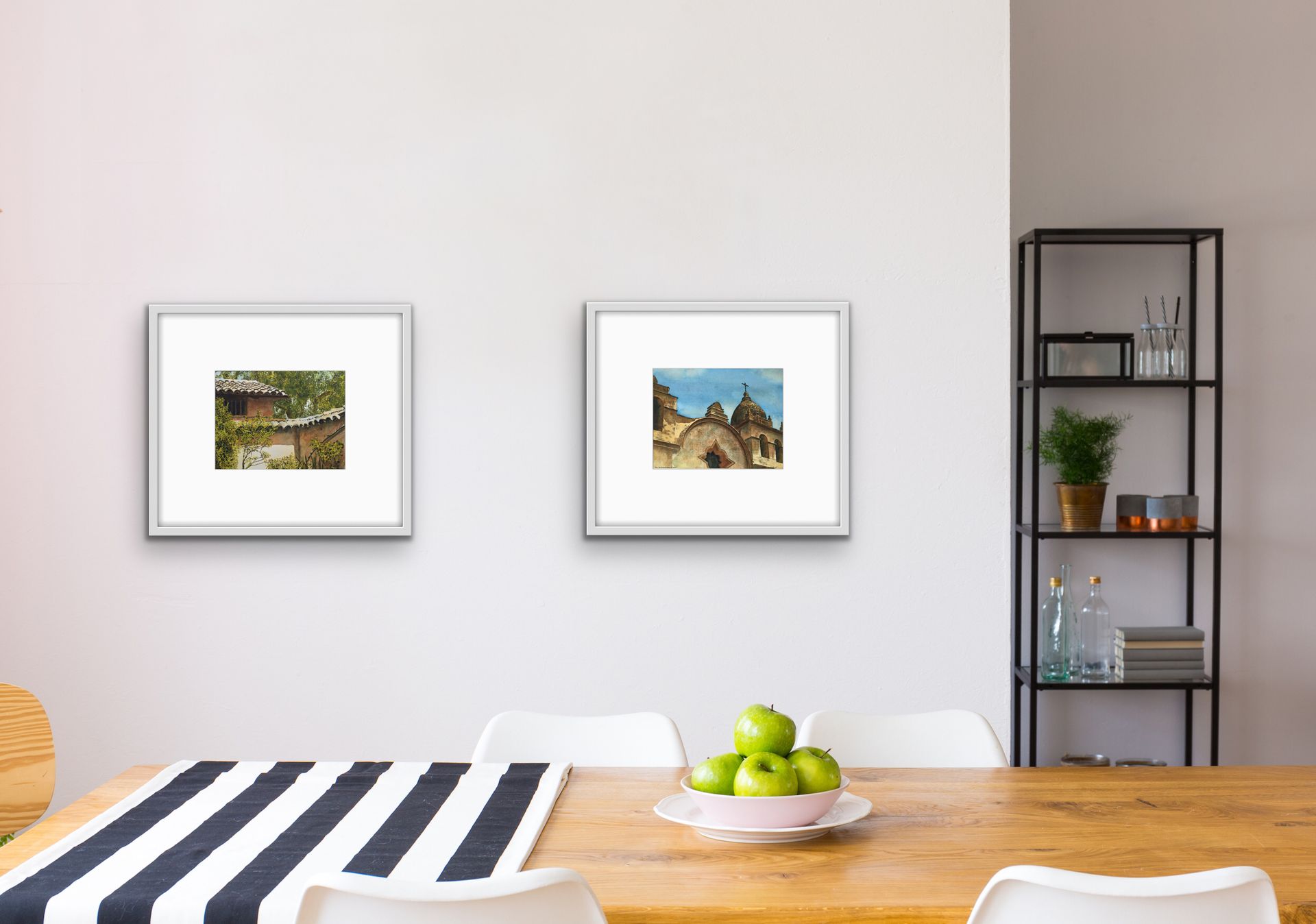 Minimal dining room with two framed pictures, a striped tablecloth, fruit bowl, and shelf with plants.