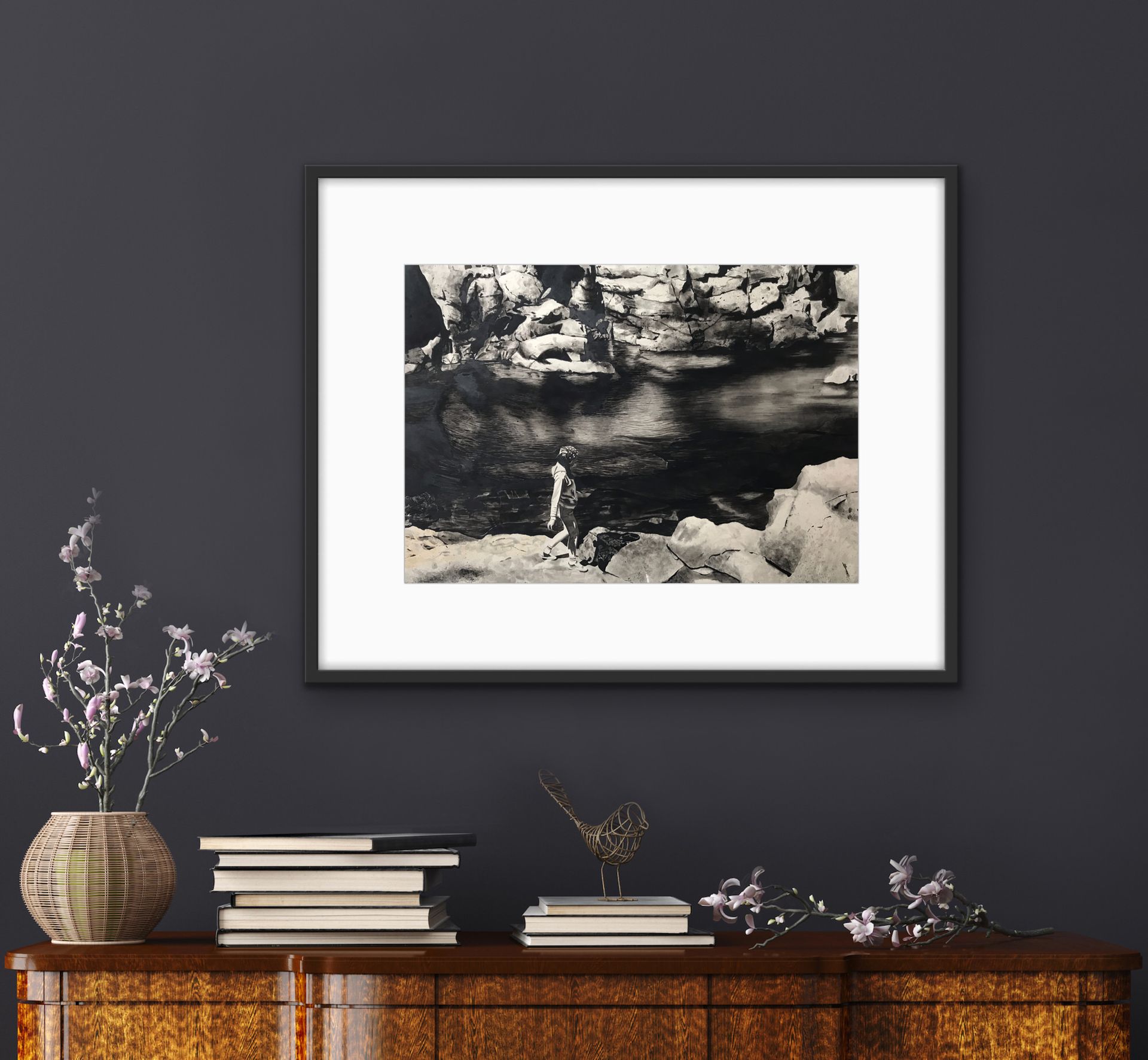 Framed black-and-white landscape print above a wooden console with books and a vase of flowers