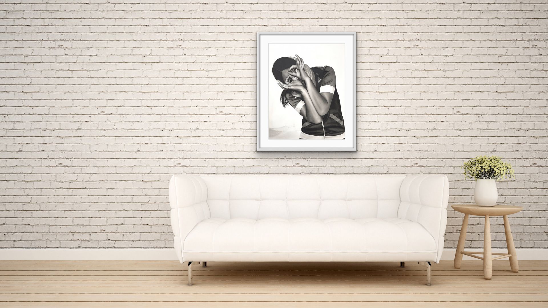 Minimalist living room with a white sofa, framed black-and-white artwork, and small side table with flowers.