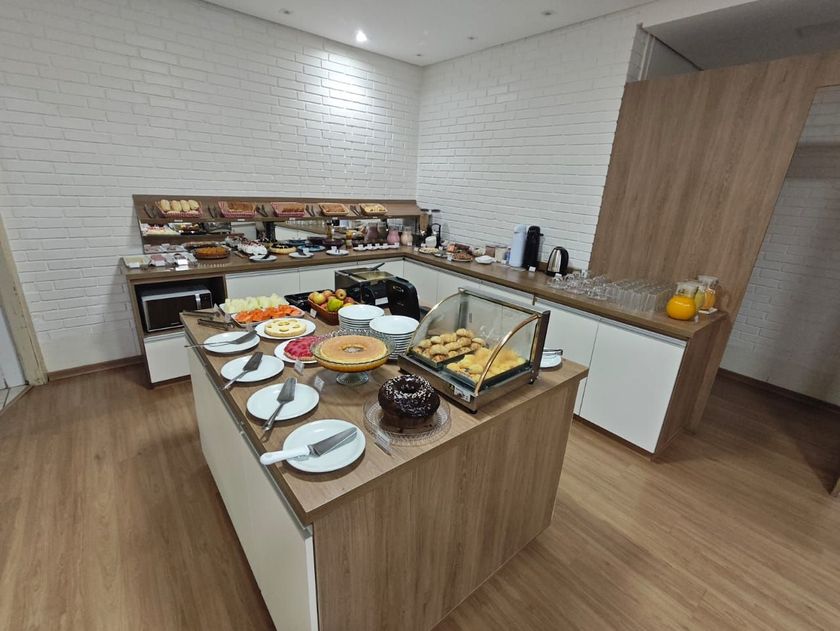 Mesa de buffet com uma variedade de doces e pratos em uma sala de jantar moderna.