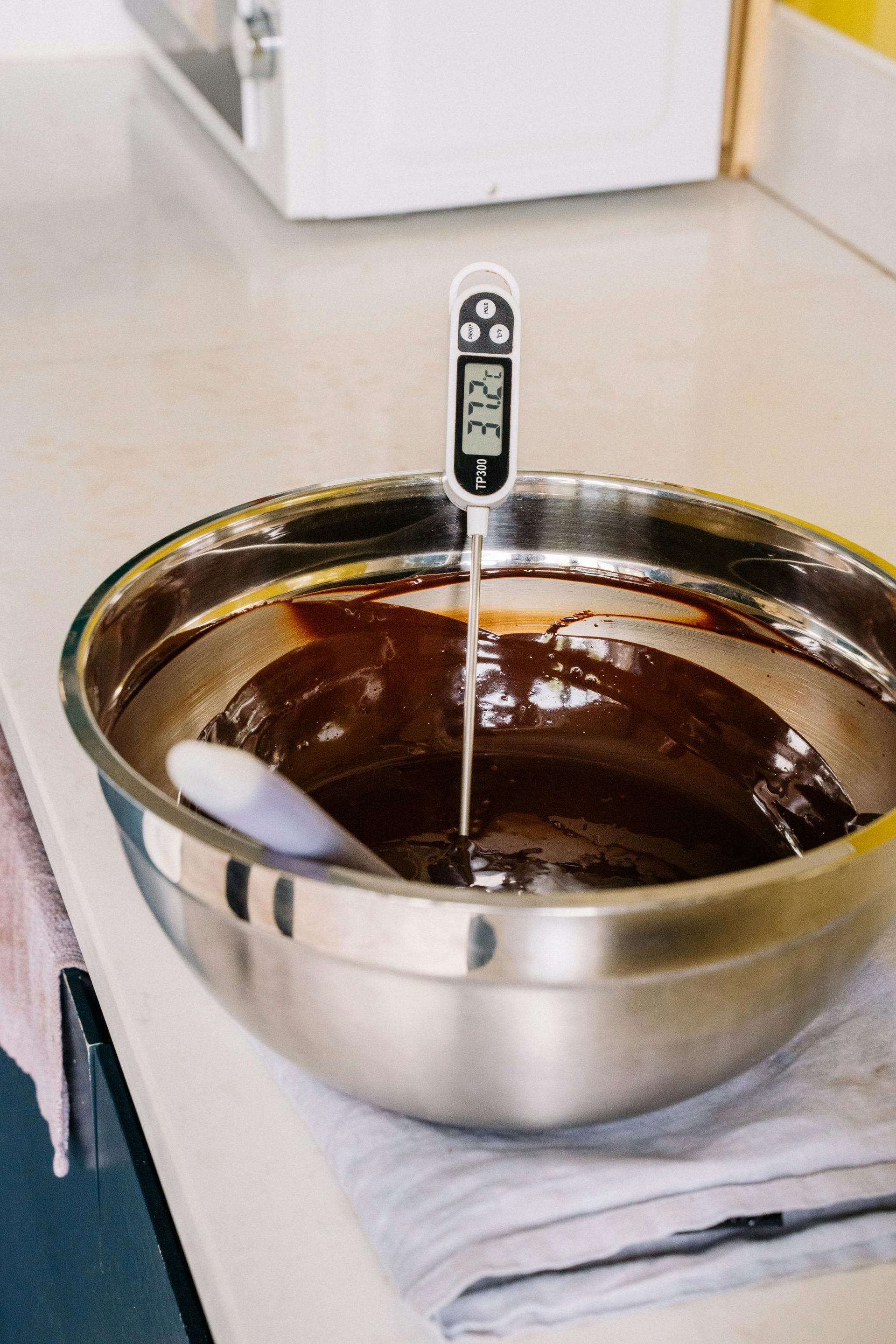A thermometer is sticking out of a bowl of chocolate.