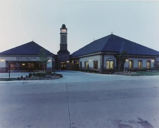 Two-story building with blue roofs and central tower at dusk