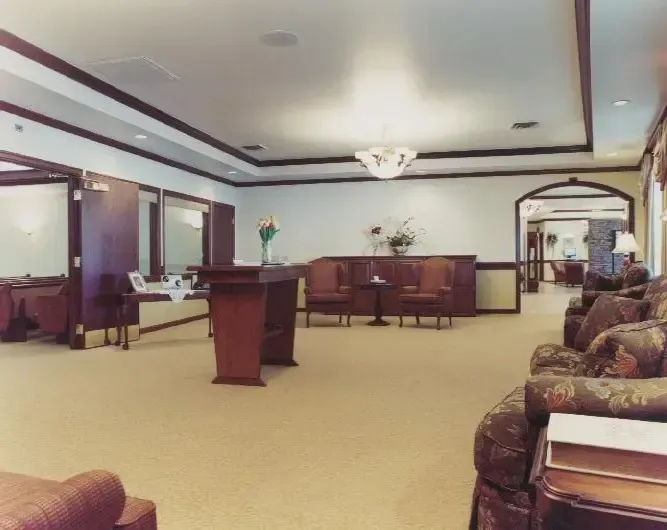 Spacious beige waiting room with wood chairs, a central lectern, and a large wall mirror