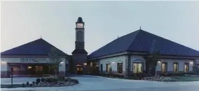 Twin building entrance at dusk with a central tower and lit windows in snowy surroundings