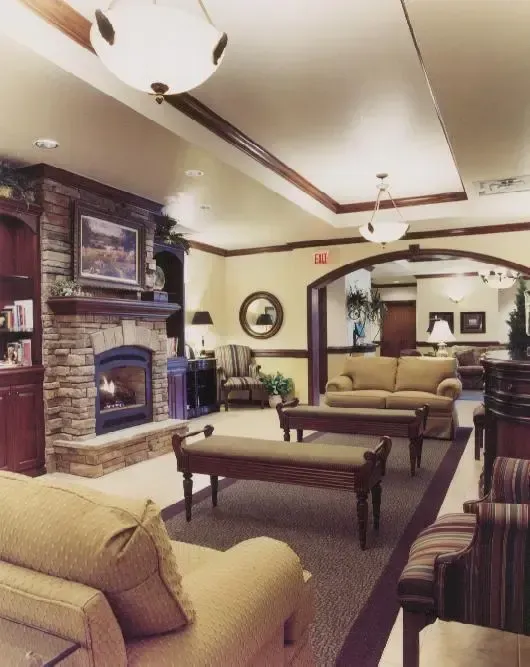 Elegant living room with beige sofas, dark fireplace, coffee tables, and warm recessed lighting
