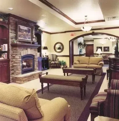 Cozy living room with brick fireplace, beige sofas, coffee table, and warm overhead lighting