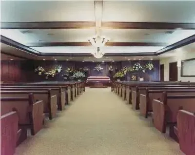 Empty church interior with wooden pews, central aisle, and altar at the front