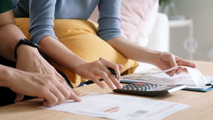 People pointing at papers and a calculator on a desk during a budget discussion