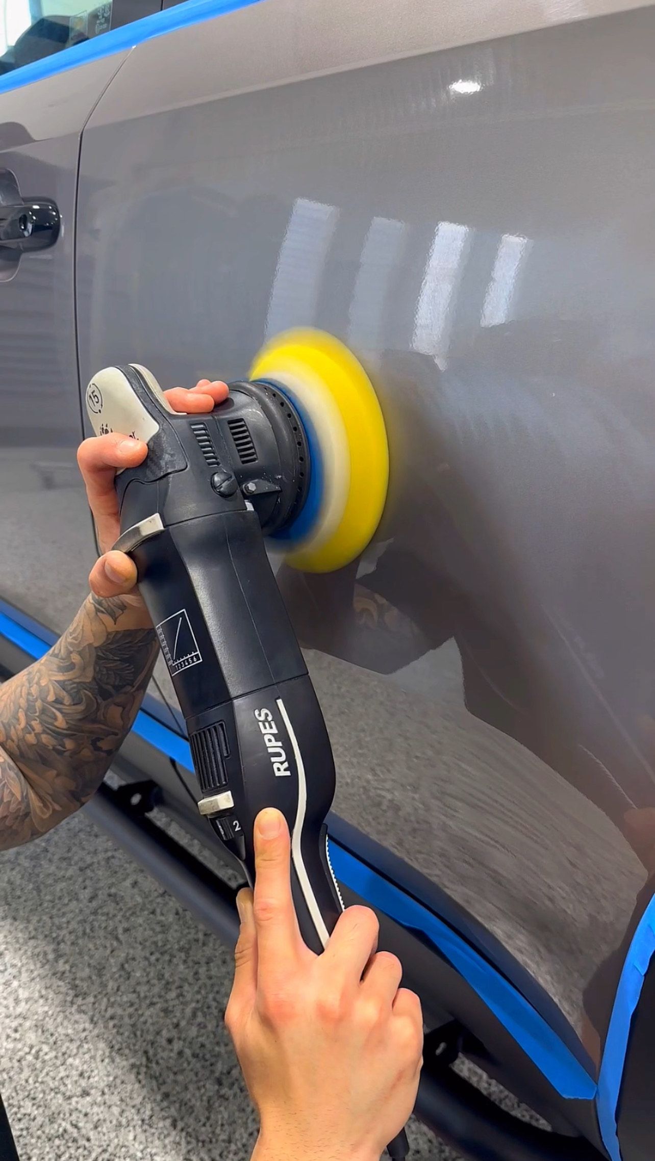A person is polishing a car with a machine.