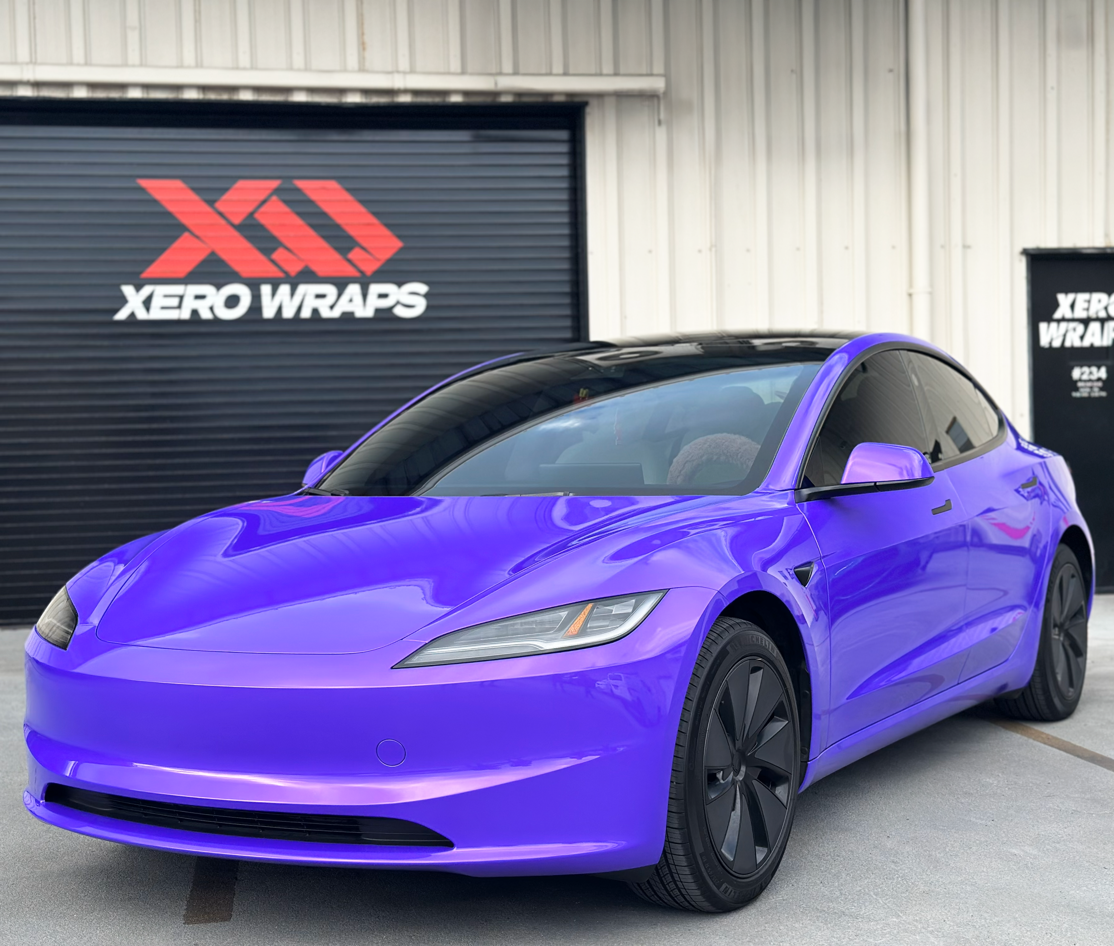 A rainbow colored car is parked in front of a building