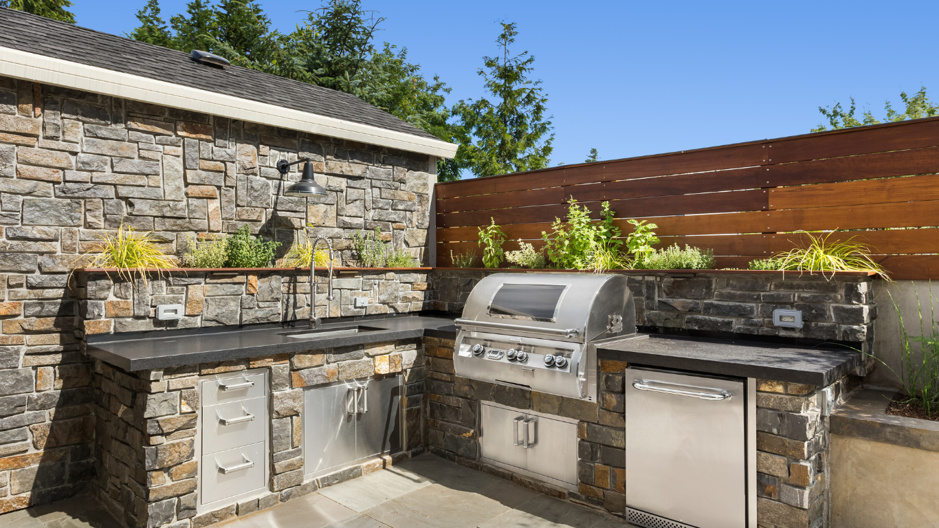 An outdoor kitchen with a grill , sink , and dishwasher.