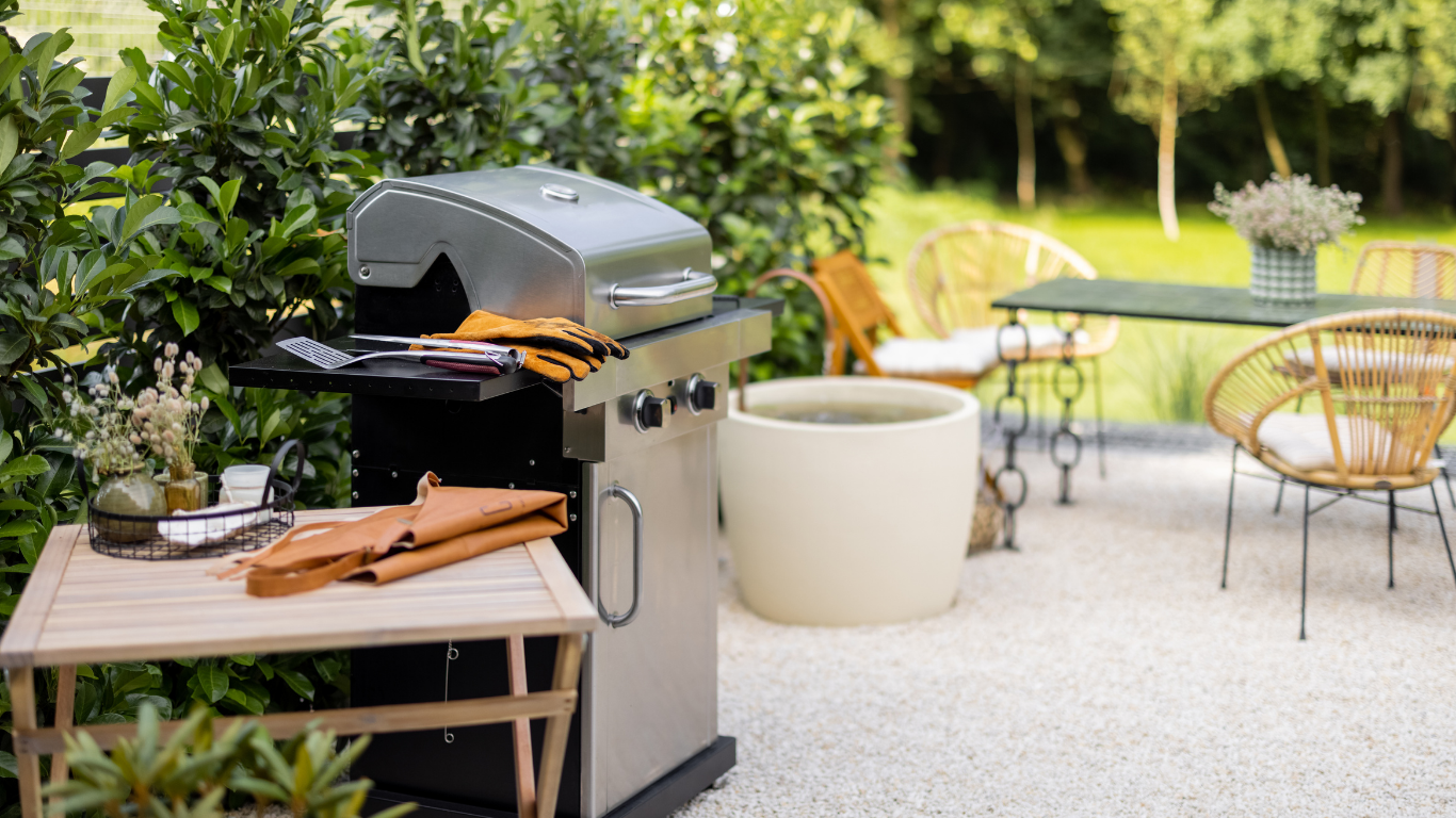 A grill is sitting on a patio next to a table and chairs.
