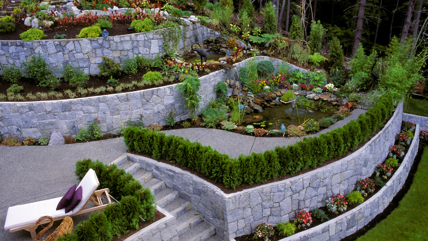 A lush green garden with a stone wall and stairs